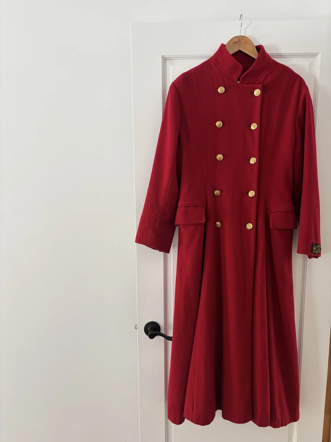 Un manteau rouge à boutons dorés sur un cintre